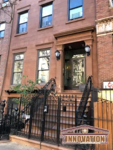 Artisan mason restoring brownstone facade with traditional tools