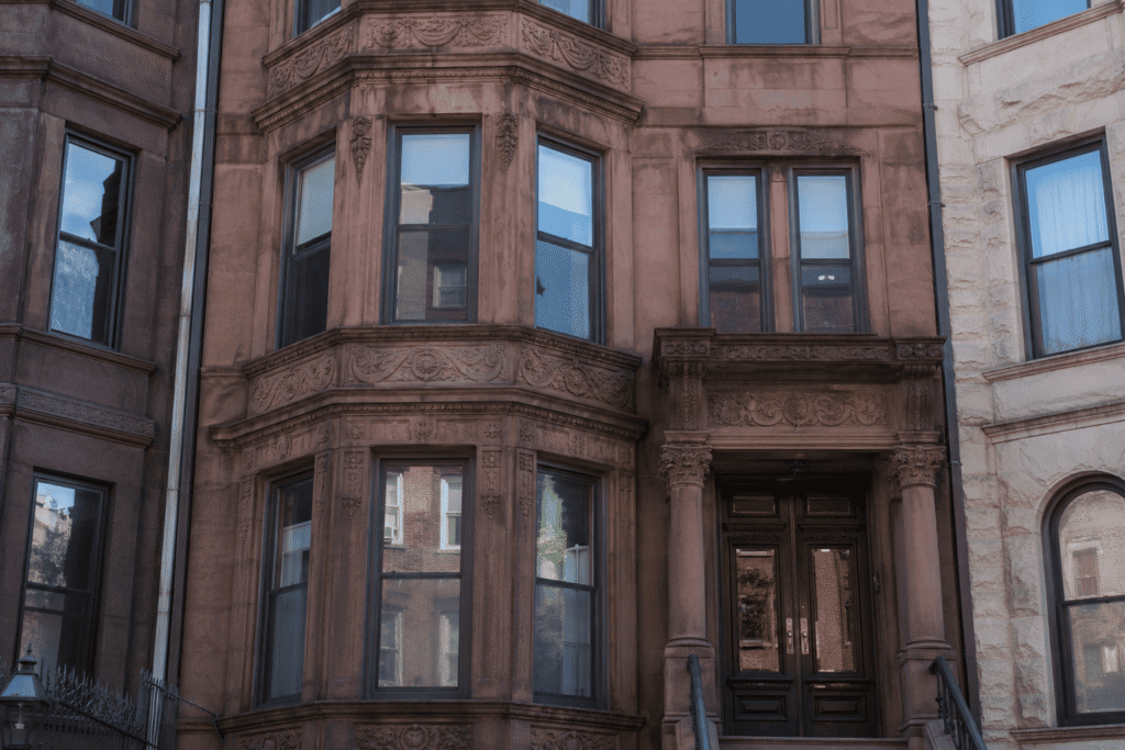 Close-up of a Harlem brownstone restoration project featuring a restored historic brownstone facade with detailed masonry and limestone architectural elements in NYC.