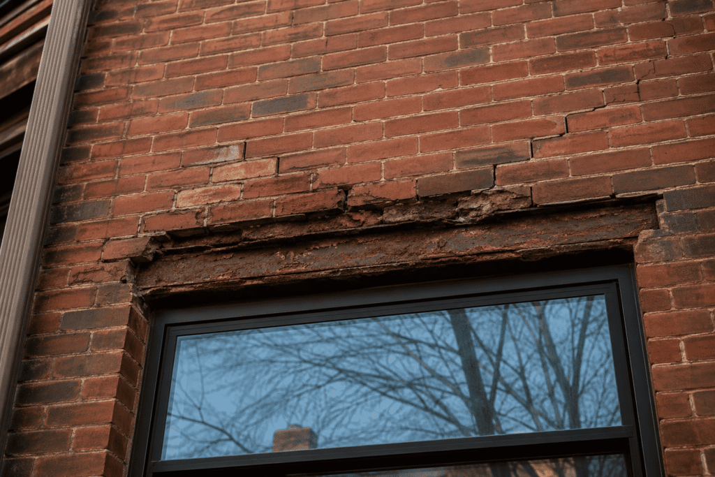 Lintel Replacement NYC showing rusted steel lintel, cracked brick masonry, and window header before structural repair